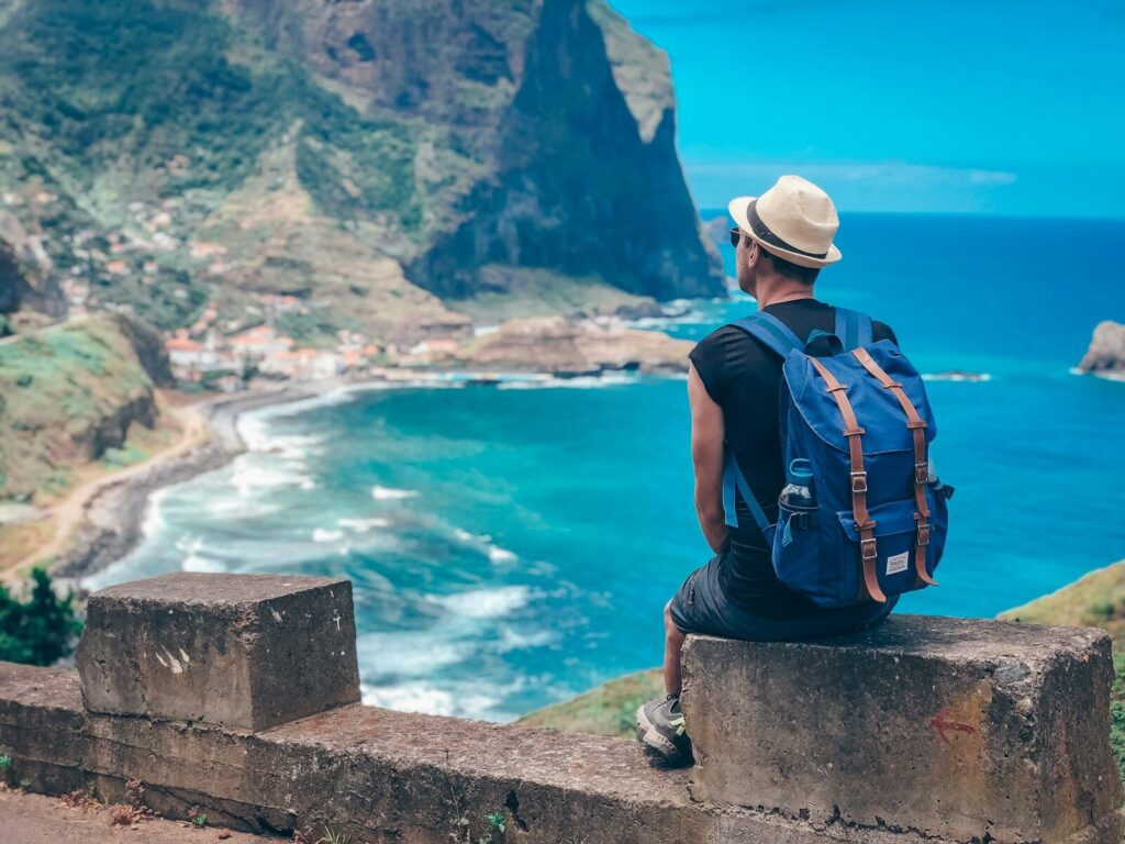 Man with backpack overlooks coastal village and ocean